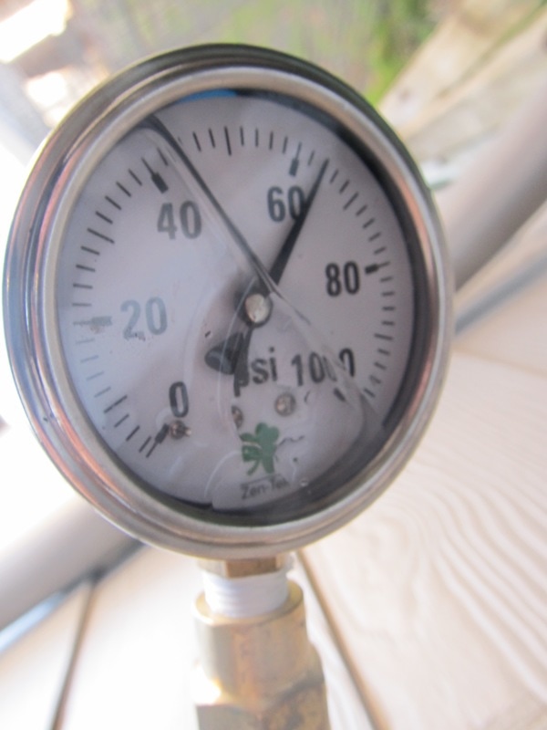 Water pressure gauge attached to an outdoor hose bib. Pressure reading is 62 PSI.